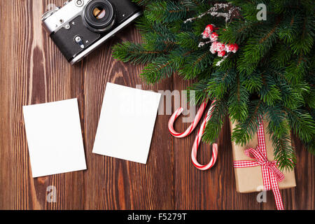 Leere Bilderrahmen mit Weihnachts-Geschenk-Box, Pinie und Kamera auf Holztisch. Ansicht von oben Stockfoto