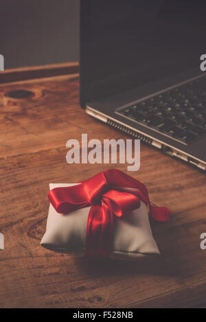 Büro-Jubiläums-Überraschung für Mitarbeiter, gewickelt auf hölzernen Schreibtisch mit Laptop-Computer im Hintergrund, Retro-getönten vorhanden Stockfoto