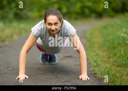 Junge Mädchen tun Push-ups aus dem Boden, ein warmes bevor Ihr Joggen im Freien. Stockfoto