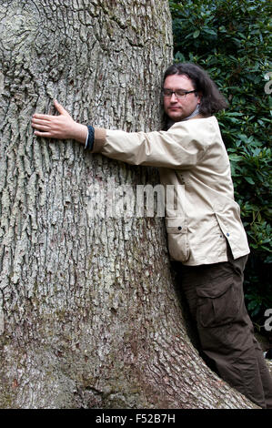 Man gibt einem riesigen Baum eine Umarmung Stockfoto