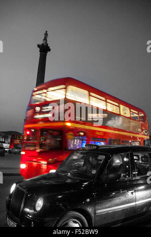 Trafalgar Square traditionelle rote Routemaster Bus und schwarzes Taxi Taxi vorbei Nelson Säule in der Nacht London England UK schwarz und Stockfoto