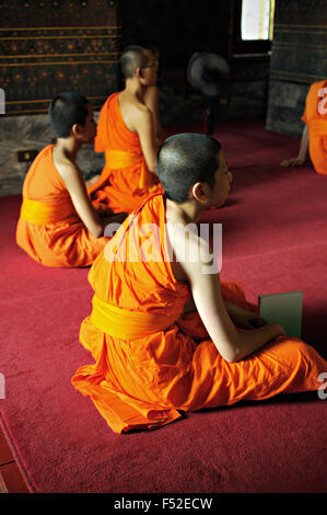 Junge buddhistische Mönche sitzen in Wat Pho (Wat Phra Chetuphon), Bangkok, Thailand Stockfoto