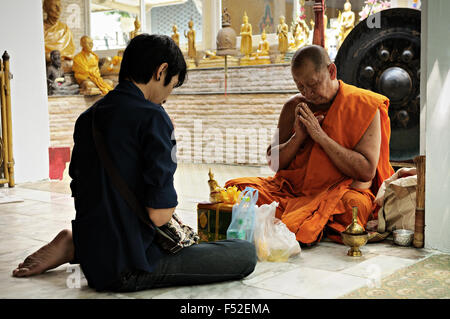 Junger Mann mit einem Mönch sitzen auf dem Boden beten am Wat Sunthorn Thammathan, Bangkok, Thailand Stockfoto