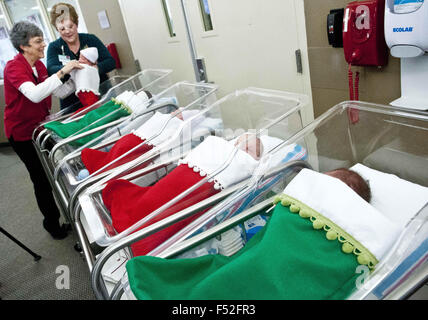 Albuquerque, New Mexico, USA. 24. Dezember 2014. Freiwillige DEBBIE COOK, links, und CAROLYN grün, Recht, ein Krankenhaus-Arbeiter, ein neugeborenes Baby Kleid in einen Strumpf in der Mutter-Baby-Einheit im Presbyterian Hospital. Für den letzten 35 Jahren haben Babys geboren am Presbyterian Hospital am Heiligabend und Weihnachten handgefertigte Weihnachtsstrümpfe gegeben. In diesem Jahr Freiwilligen gemacht 34 Strümpfe. © Marla Brose/Albuquerque Journal/ZUMA Draht/Alamy Live-Nachrichten Stockfoto