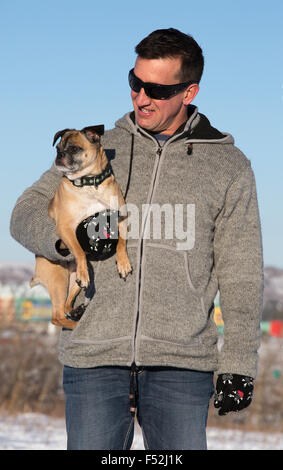 Mann hält Bugg Hund im Stadtpark (Kreuzung zwischen Boston Terrier und Mops) Stockfoto