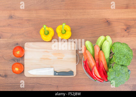 frisches Gemüse und Messer auf Schneidebrett auf Holztisch Stockfoto