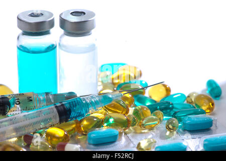 Blaue, gelbe und rote Gelatinekapseln, Glasfläschchen und Spritzen. Stockfoto