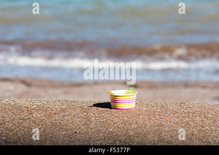 Eine leere Eis Badewanne mit zwei Plastik Löffel auf Schritte am Meer Stockfoto