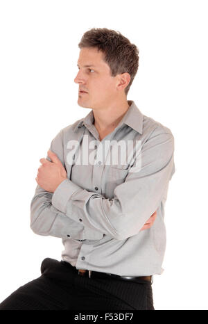 Ein junger Geschäftsmann sitzt mit seinen Händen über seine Brust, in einem grauen Hemd hochgerechnet für weißen Hintergrund isoliert. Stockfoto