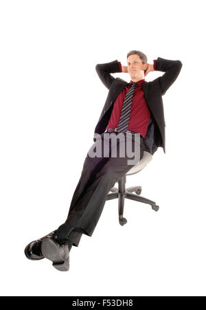 Ein Geschäftsmann im Anzug sitzen in einem Bürostuhl, lehnt sich zurück mit seinen Händen hinter dem Kopf isoliert auf weißem Hintergrund. Stockfoto