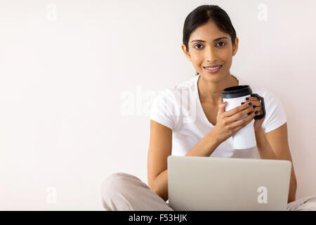 moderne junge indische Frau Kaffee trinken, während mit Laptop zu Hause Stockfoto