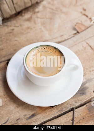 Doppelter Espresso in eine weiße Tasse über einem Dhau Holztisch gelegt. Erhöhten Blick, vertikale Ausrichtung. Stockfoto