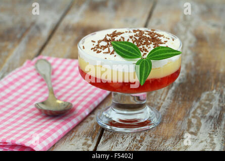 Traditionelle englische Erdbeer Trifle in transparenten Dessert Glas auf rustikalen Holzoberfläche Stockfoto