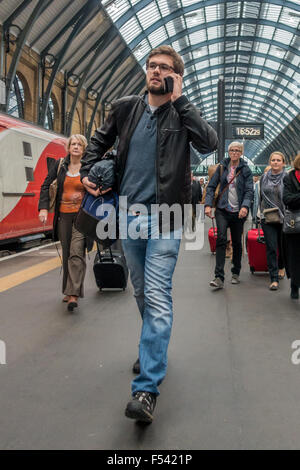 Mann am Telefon den Bahnsteig an der Kings Cross Station entlang schreiten Stockfoto