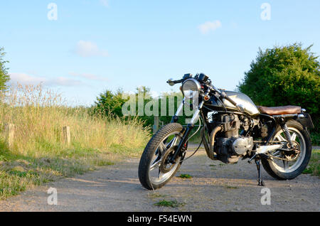 Honda Cafe Racer Motorrad schwarz fotografiert vor einem Feld Gras Stockfoto