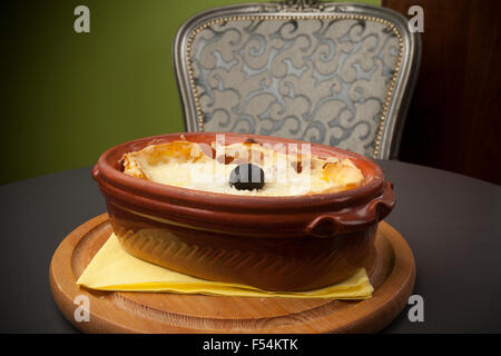 Portion Lasagne in einem Keramiktopf auf einem Holzsockel Stockfoto