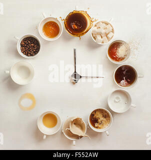 Kaffee Clock.Clock gemacht von einem Dutzend Tassen Kaffee (mit Kaffeebohnen, Milch und Spritzer). Es ist immer Kaffeezeit! Stockfoto