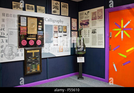 Keswick Pencil Museum.  Wand-Display Kalligraphie und eine Fliegen-Presse neben Tür dekoriert mit Bleistiften. Cumbria, England UK Stockfoto