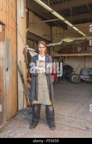 Porträt von zuversichtlich weibliche Mechaniker stehend Arme gekreuzt in der garage Stockfoto