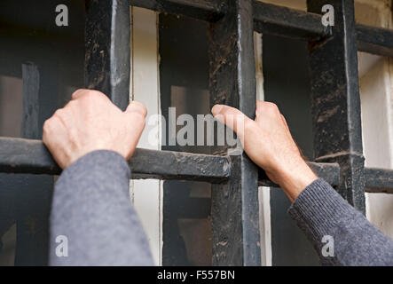 Nahaufnahme eines Mannes, der Metallstangen am Fenster hält Stockfoto