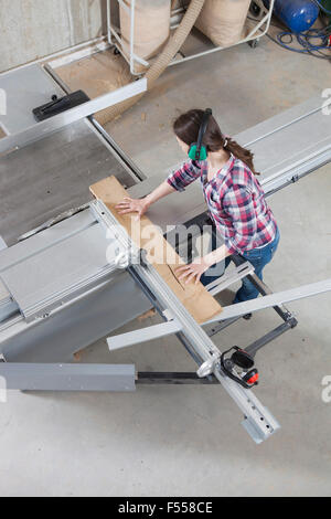 Frau Zimmermann mit einem Schiebetisch sah in einer Werkstatt Stockfoto