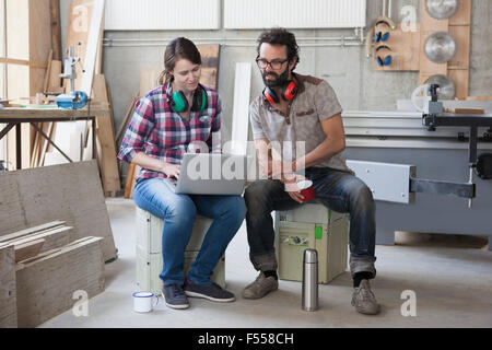 Voller Länge Mitte Erwachsenen Tischler mit Laptop in Werkstatt Stockfoto