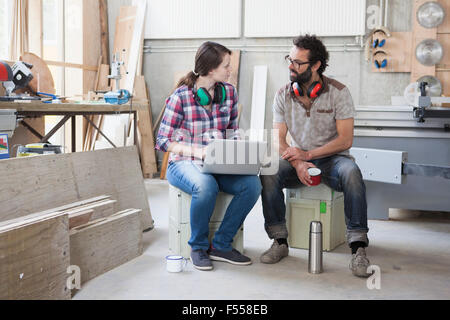 Voller Länge Mitte Erwachsenen Tischler während mit Laptop im Workshop diskutieren Stockfoto