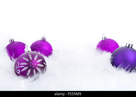 Lila Weihnachtskugeln auf eine weiche federleichte Oberfläche mit einem weißen Hintergrund. Stockfoto