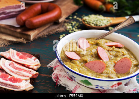 Herzhafte traditionelle holländische Erbsensuppe mit geräucherter Wurst, Roggenbrot und Speck. Oder: 'Erwtensoep met Rookworst, Roggebrood En Spek'. Stockfoto