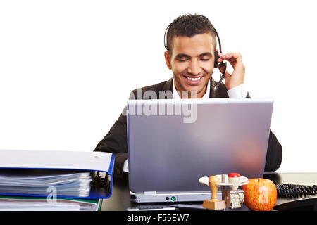 Junge Manager, die mit einem Laptop mit einem Kopfhörer Stockfoto