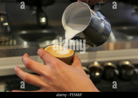 Händen der Barista als er eine Tasse Cappuccino bereitet Stockfoto