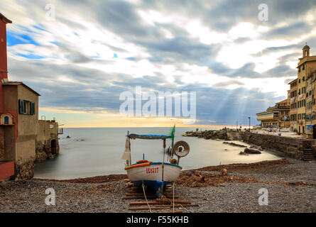 Kleines Boot an Land am Strand von Boccadassa, ein beliebtes kleines Fischerdorf in Genua, Italien mit den Sonnenuntergang über einem ruhigen o Stockfoto