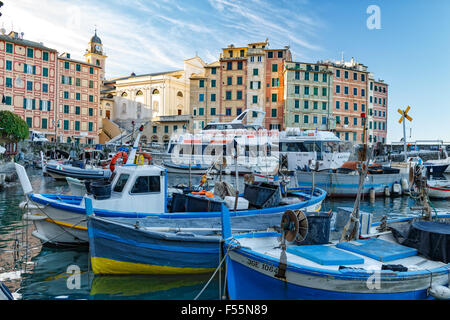 Kleine Fischerboote vertäut im Hafen von Camogli, überragt von bunten Uferpromenade Gebäuden in diesem beliebten Ferienort Stockfoto