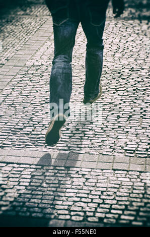 Geheimnisvolle Mann läuft auf einer gepflasterten Straße Stockfoto