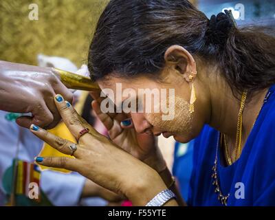 Yangon, Yangon Division, Myanmar. 28. Oktober 2015. Eine Frau betet durch Berühren der Stirn am Finger einer Statue während Gedenktage des Thadingyut am Botataung-Pagode in Yangon. Botataung Pagode wurde zuerst durch die Mon, eine burmesische ethnische Minderheit, etwa zur gleichen Zeit gebaut, als Shwedagon-Pagode, vor über 2500 Jahren wurde. Das Thadingyut Festival, die Beleuchtung Festival von Myanmar, ist am Vollmondtag des birmanischen lunaren Monats des Thadingyut statt. Als ein Brauch ist es am Ende der buddhistischen Fastenzeit (Vassa) statt. Das Thadingyut Festival ist die Feier, die Buddha Abstieg vom Bun begrüßen zu dürfen Stockfoto