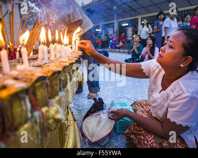 Yangon, Yangon Division, Myanmar. 28. Oktober 2015. Eine Frau-Lichter-Kerzen während des Betens auf eine Statue des Buddha während Gedenktage des Thadingyut am Botataung-Pagode in Yangon. Botataung Pagode wurde zuerst durch die Mon, eine burmesische ethnische Minderheit, etwa zur gleichen Zeit gebaut, als Shwedagon-Pagode, vor über 2500 Jahren wurde. Das Thadingyut Festival, die Beleuchtung Festival von Myanmar, ist am Vollmondtag des birmanischen lunaren Monats des Thadingyut statt. Als ein Brauch ist es am Ende der buddhistischen Fastenzeit (Vassa) statt. Das Thadingyut Festival ist das Fest Buddhas Abstieg vom Himmel willkommen Stockfoto