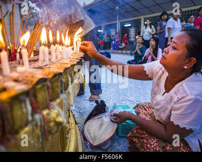 Yangon, Yangon Division, Myanmar. 28. Oktober 2015. Eine Frau-Lichter-Kerzen während des Betens auf eine Statue des Buddha während Gedenktage des Thadingyut am Botataung-Pagode in Yangon. Botataung Pagode wurde zuerst durch die Mon, eine burmesische ethnische Minderheit, etwa zur gleichen Zeit gebaut, als Shwedagon-Pagode, vor über 2500 Jahren wurde. Das Thadingyut Festival, die Beleuchtung Festival von Myanmar, ist am Vollmondtag des birmanischen lunaren Monats des Thadingyut statt. Als ein Brauch ist es am Ende der buddhistischen Fastenzeit (Vassa) statt. Das Thadingyut Festival ist das Fest Buddhas Abstieg vom Himmel willkommen Stockfoto