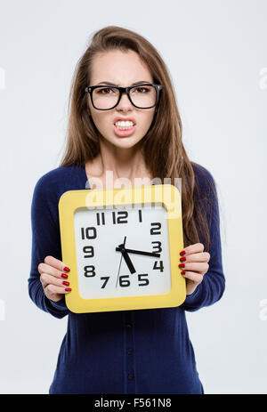 Porträt von wütenden Frau hält Wanduhr isoliert auf weißem Hintergrund Stockfoto