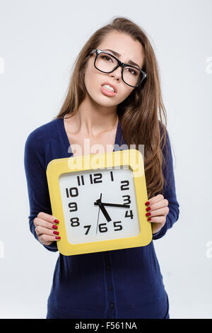 Porträt einer traurigen Frau mit Wanduhr isoliert auf weißem Hintergrund Stockfoto