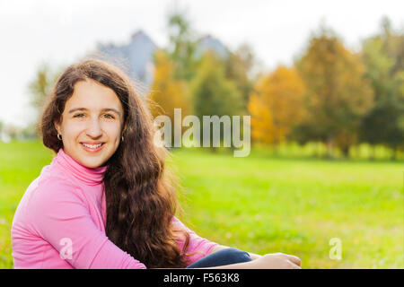 Schöne Mädchen Nahaufnahme sitzt auf dem grünen Rasen Stockfoto