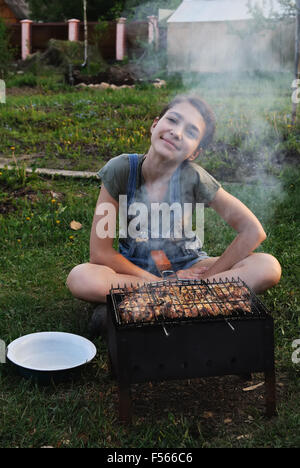 Mädchen Braten Sie das Fleisch auf dem Grill in der Sommer-Natur. Stockfoto