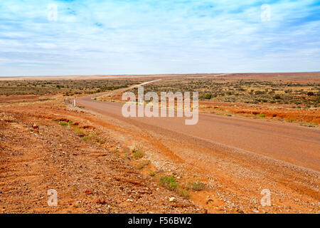 Lange Outback Straße über weiten trockenen baumlosen Landschaft zum fernen Horizont und blauer Himmel, in der Nähe von Birdsville im westlichen Queensland Stockfoto