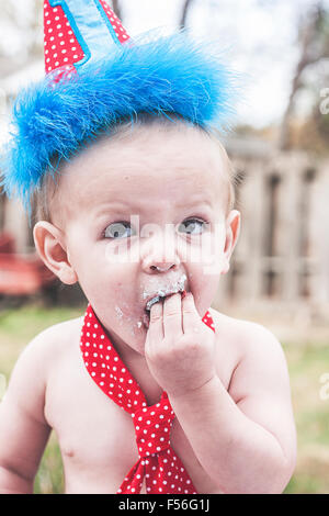 Baby Boy mit Hand und Mund zu ersten Geburtstag Kuchen Stockfoto