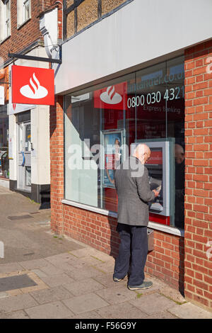 Ein Mann Bargeld von Geldautomaten der Santander in Hitchin, England, Vereinigtes Königreich UK Stockfoto