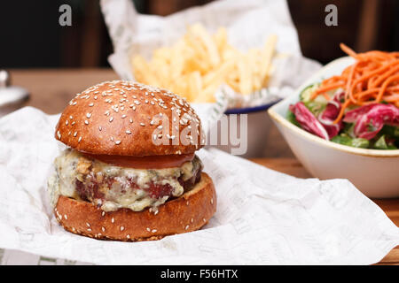 Beef-Burger in einem Sesam Brötchen mit einer Portion Salat und Pommes frites Stockfoto