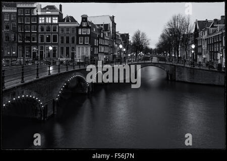 schwarz / weiß Bild mit den berühmten Grachten und Brücken von Amsterdam nach Einbruch der Dunkelheit eine Langzeitbelichtung horizontales Bild. Stockfoto