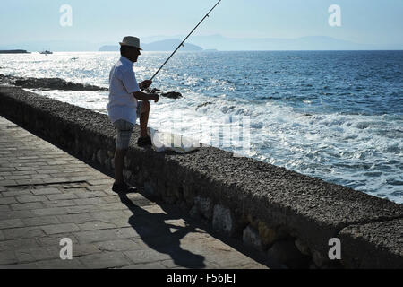 Ein Fischer versucht geduldig sein Glück entlang der Uferpromenade von Chania auf Kreta in Griechenland Stockfoto