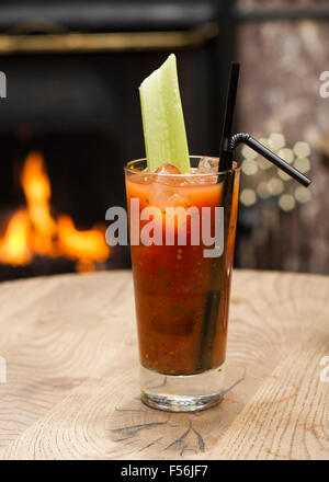 Bloody Mary Cocktail mit einer Selleriestange vor einem offenen Kamin Stockfoto