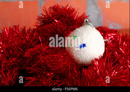 weiß verschneiten Weihnachtskugel in der roten Nadeln Stockfoto