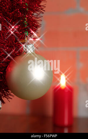 Silber glänzend hängen Weihnachtskugel gegen die brennende Kerze Stockfoto